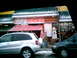 1997 Ford Escort - A street view shows a storefront with various signs and awnings, with two vehicles passing by.