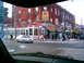 1997 Ford Escort - A silver sedan drives through a city intersection with pedestrians and businesses visible.