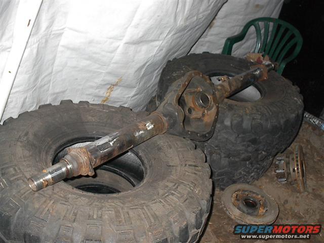 Rusty axle assembly and large tires stacked indoors