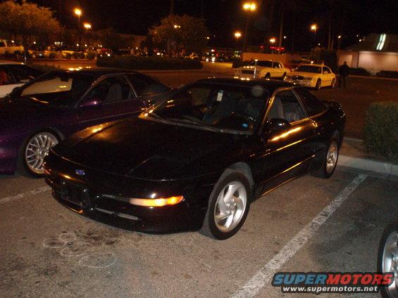 Black 1997 Ford Probe parked at night next to a purple car