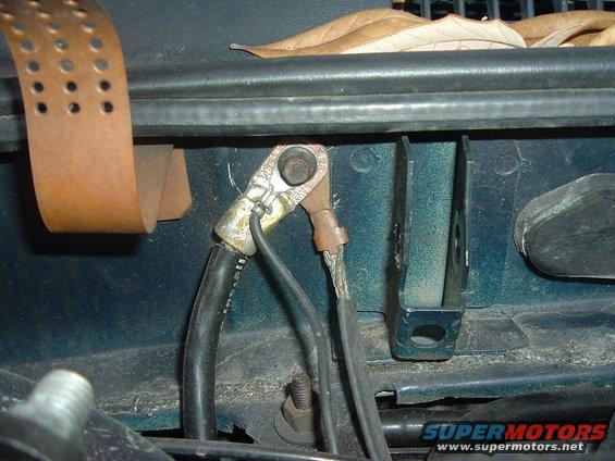 close-up of car battery cables connected to terminals, with some leaves on top