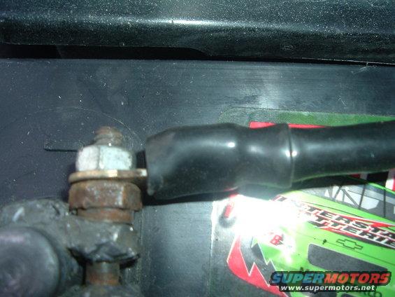 Battery cable terminal with rust and a black protective boot, attached to a black battery with an Interstate Batteries label