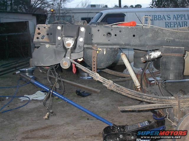 Truck frame and suspension components, including leaf springs and airbags, with a floor jack underneath