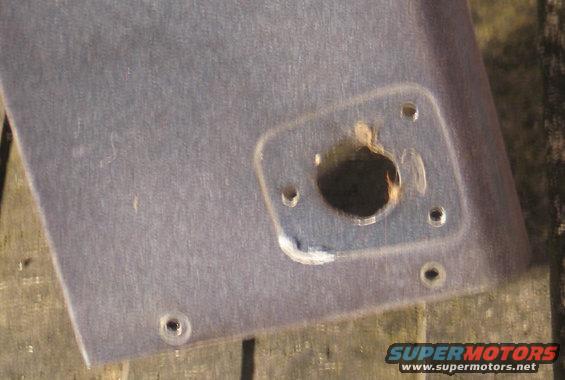 Close-up of a gray interior panel with a circular hole and mounting points