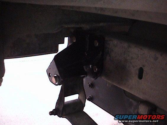 Close-up of a black lift kit component bolted to a vehicle's frame and leaf spring