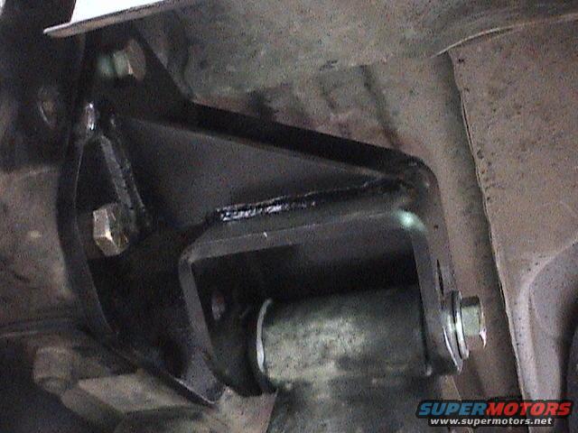 Black metal suspension bracket with bolts attached to vehicle undercarriage