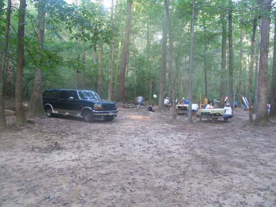 Black Ford Econoline conversion van parked in a wooded campsite