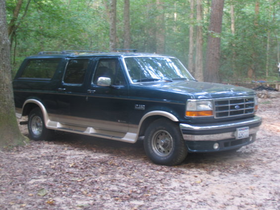 1995 Ford C-150 Centurion Conversions SUV, dark green with tan trim, parked in woods