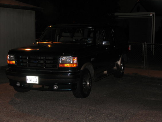 Dark green Ford F-150 parked at night. License plate reads 6DW 011
