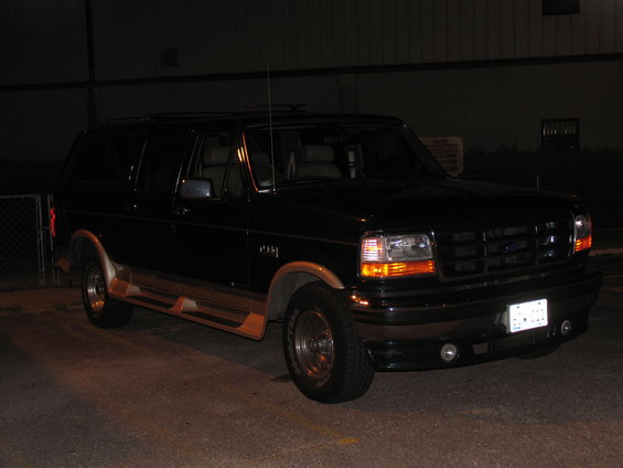 Black Ford Bronco with woodgrain trim and running boards, parked at night