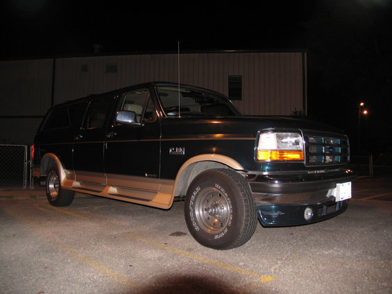 Dark green Ford Econoline conversion van with tan trim, parked at night