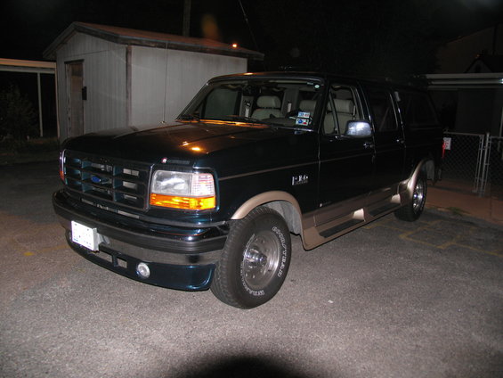 Dark green 1995 Ford C-150 conversion van with tan trim, 3/4 front view