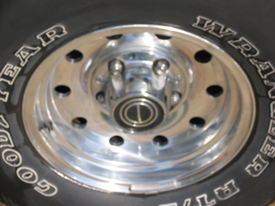 Close-up of a chrome wheel with Goodyear Wrangler tires and a black center cap with a gold emblem
