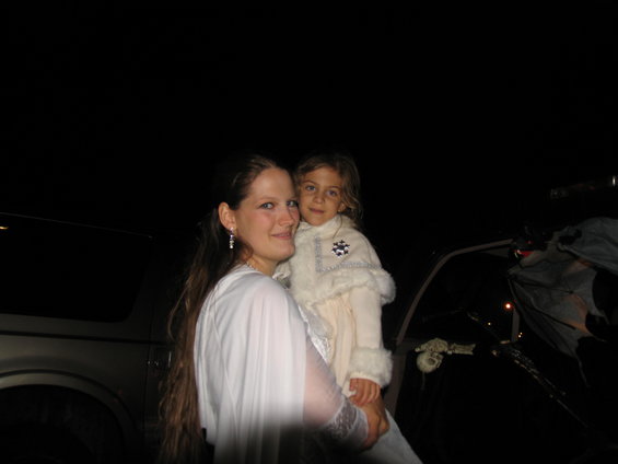 Silver SUV side view at night with a woman holding a child in front of it