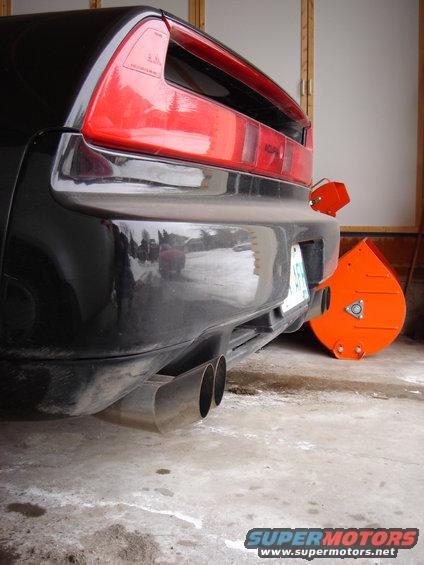 Rear of black Acura NSX with dual exhaust and an orange snow blower attachment on the bumper