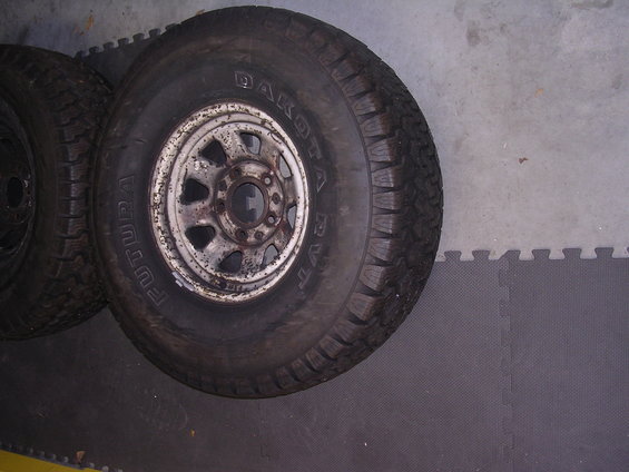 Two tires and rusty wheels on a grey floor