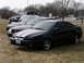 2001 Ford Crown Victoria - A black coupe with silver racing stripes is parked in a grassy lot alongside other vehicles.