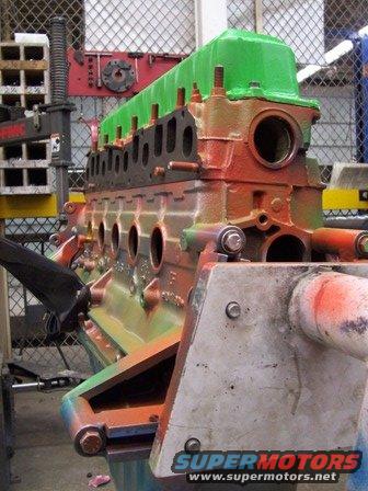 Engine block with green valve cover and orange block, mounted on stand