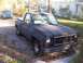 1974 Chevrolet C/K Pickup - A dark gray Chevrolet C/K Pickup truck is parked in a yard with a blue Dodge Dakota in the background.