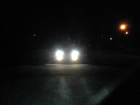 Front view of a vehicle with bright headlights on a dark road