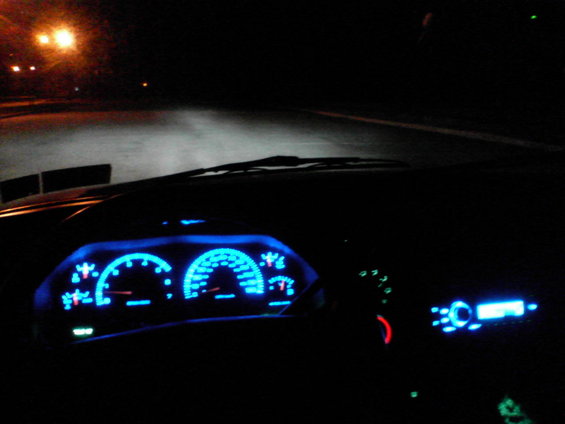 Car dashboard with blue illuminated gauges and radio display at night