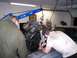 1967 Ford Mustang - Two mechanics work on an engine being hoisted out of a vehicle in a garage setting.