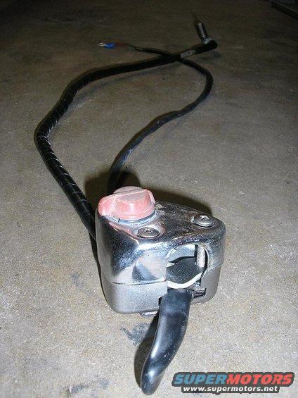 Chrome motorcycle handlebar switch assembly with a red button and black lever on a concrete surface