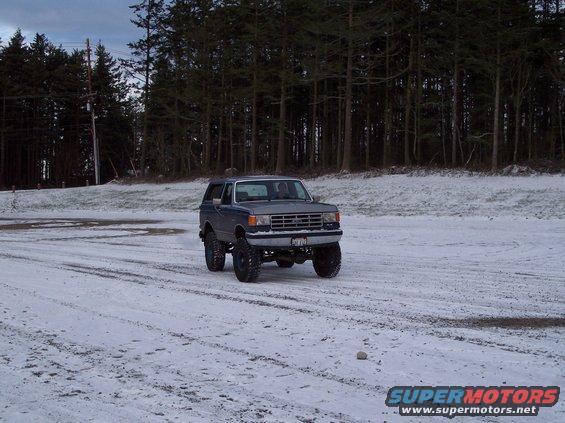 1987 Ford Bronco on snowy ground with trees in background