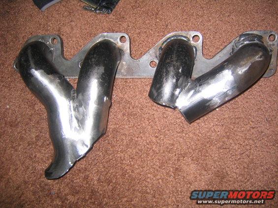 Custom exhaust manifold with two pipes on a brown carpet