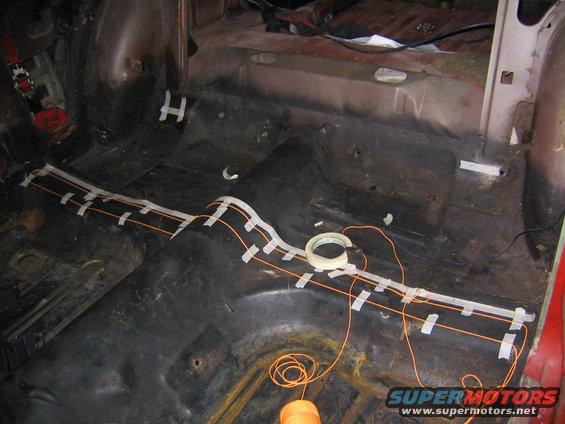 Car interior with orange wiring taped to the floor for a turbo build