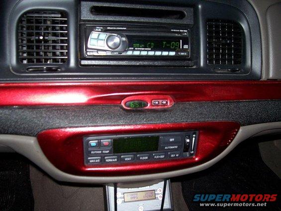 Car dashboard with aftermarket stereo, red trim, and digital clock