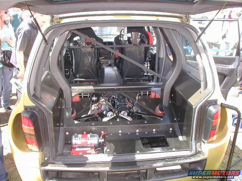 Rear view of a modified car showing racing seats, exposed engine, and custom interior panels