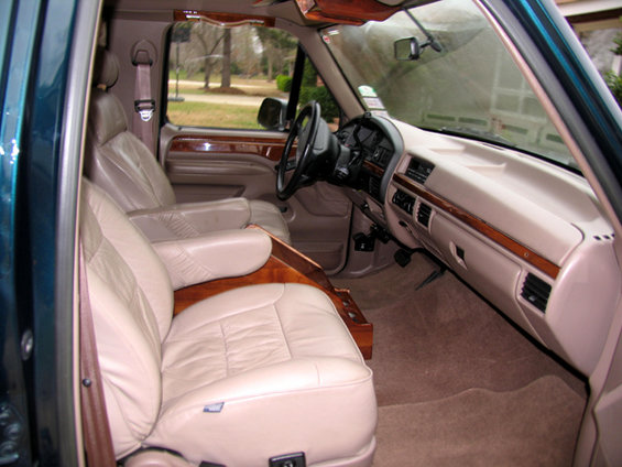 Interior view of a van with plush leather captain's chairs and wood accents