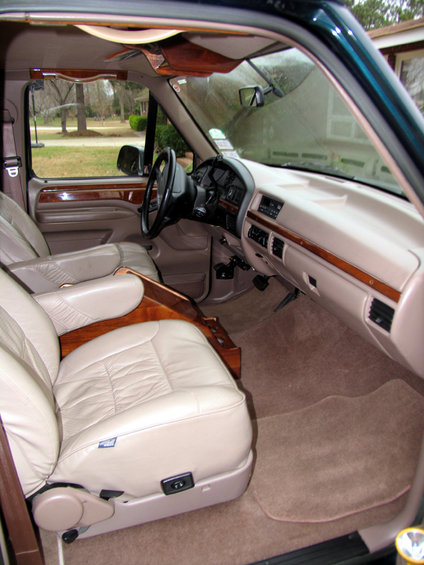 Interior of a 1995 Ford C-150 (Centurion Conversions) showing tan leather seats, wood trim, and dashboard
