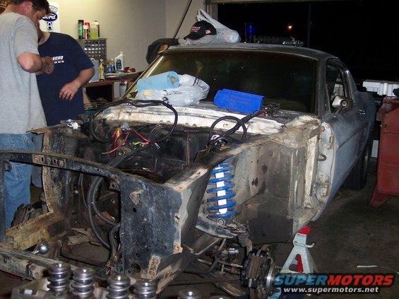 1967 Ford Mustang undergoing repairs, engine bay disassembled, front suspension visible