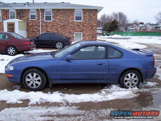Blue 1994 Honda Prelude coupe parked on a dirt lot with snow and puddles