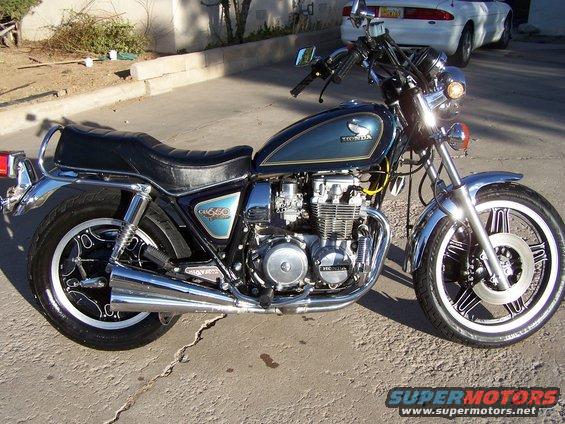Blue and silver 1981 Honda CB750 motorcycle parked on asphalt, showing chrome exhaust and engine details