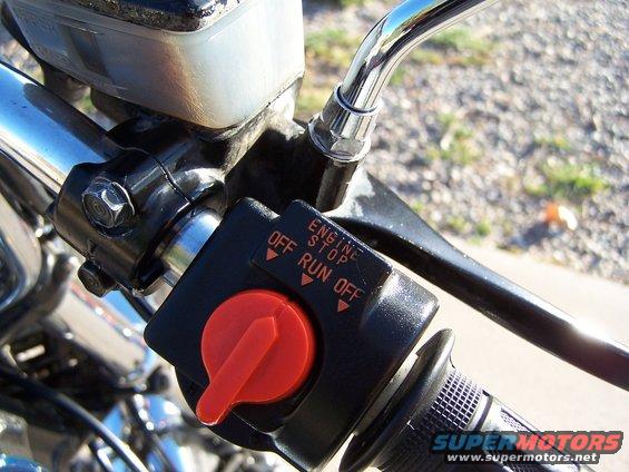 Close-up of motorcycle handlebar with engine stop switch and brake lever