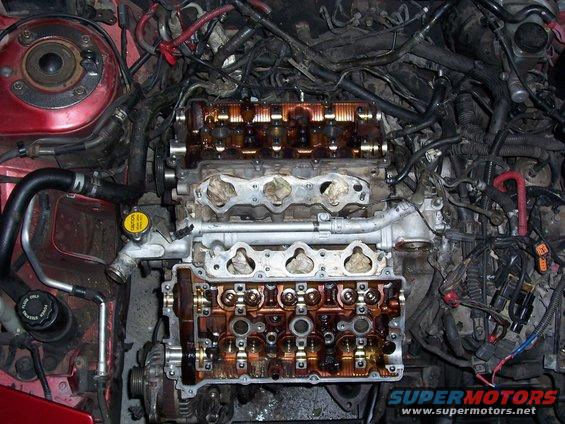Engine bay with valve covers removed, showing internal components and wiring