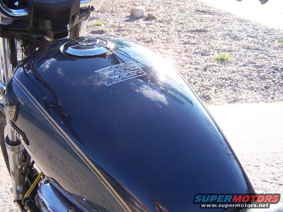 Close-up of a dark blue motorcycle fuel tank with a sticker on it