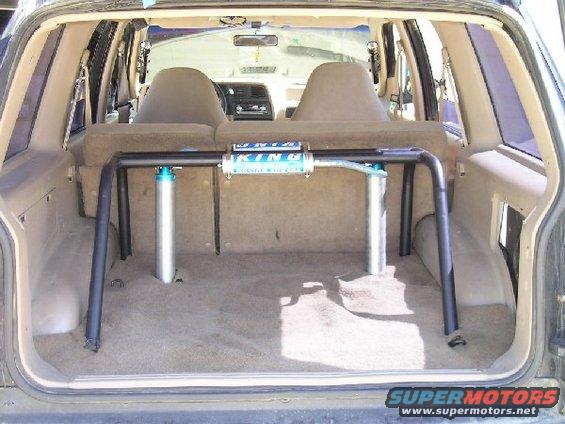 Interior view of an SUV showing a roll cage and two rear seats. A 'KING' shock absorber is mounted on the roll cage