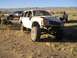 1985 Ford Bronco II - Several modified vehicles are parked in a dry, desert environment under a clear blue sky.