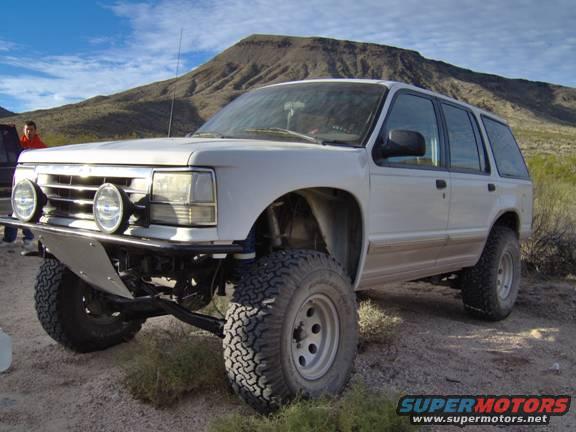 White SUV with off-road tires and custom bumper. Appears to be a 1990 Ford Explorer