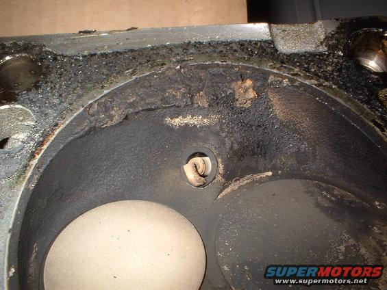Close-up of a dirty engine cylinder head with carbon buildup and a spark plug