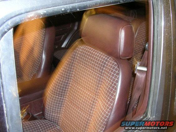 Brown plaid and leather interior of a 1984 Jeep Cherokee, showing front seats and seatbelts