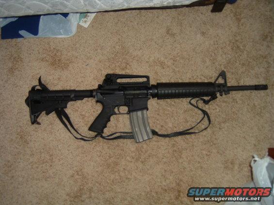 AR-15 style rifle with a sling on a carpeted floor