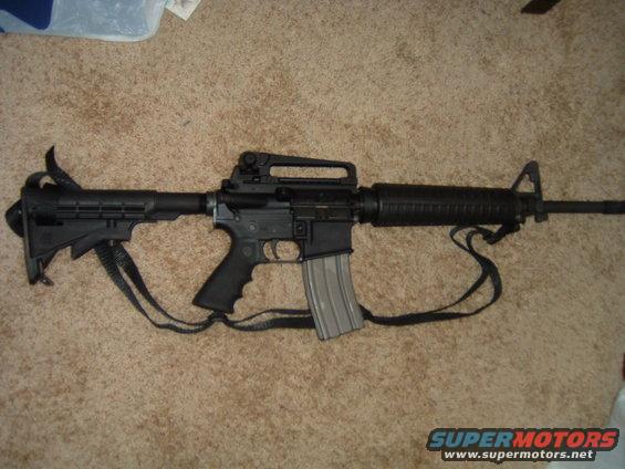 AR-15 style rifle with a sling on a carpeted floor