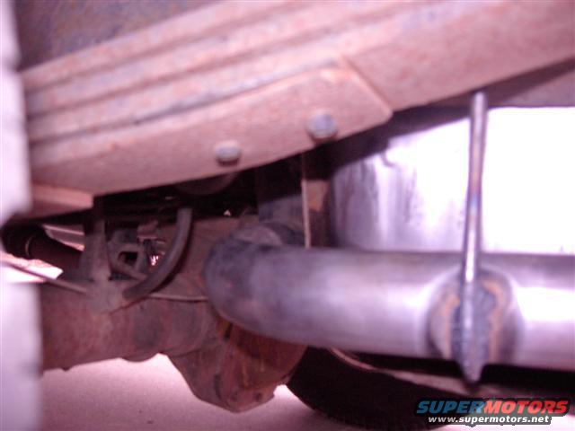 Underside of a vehicle showing rusty leaf springs, exhaust pipe, and differential