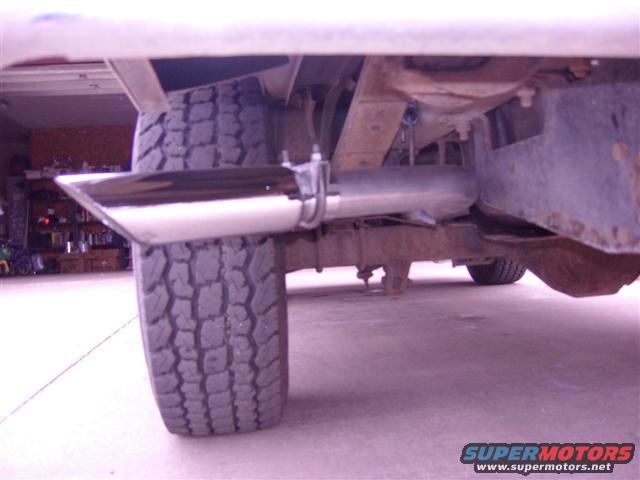 Close-up of a chrome exhaust tip and tire under a vehicle