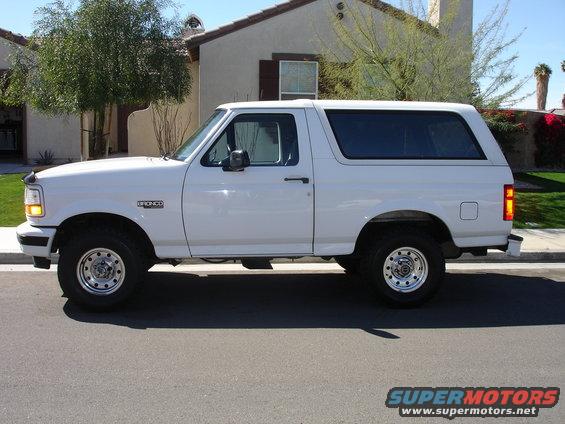 White Ford Bronco SUV, side view, parked on asphalt street